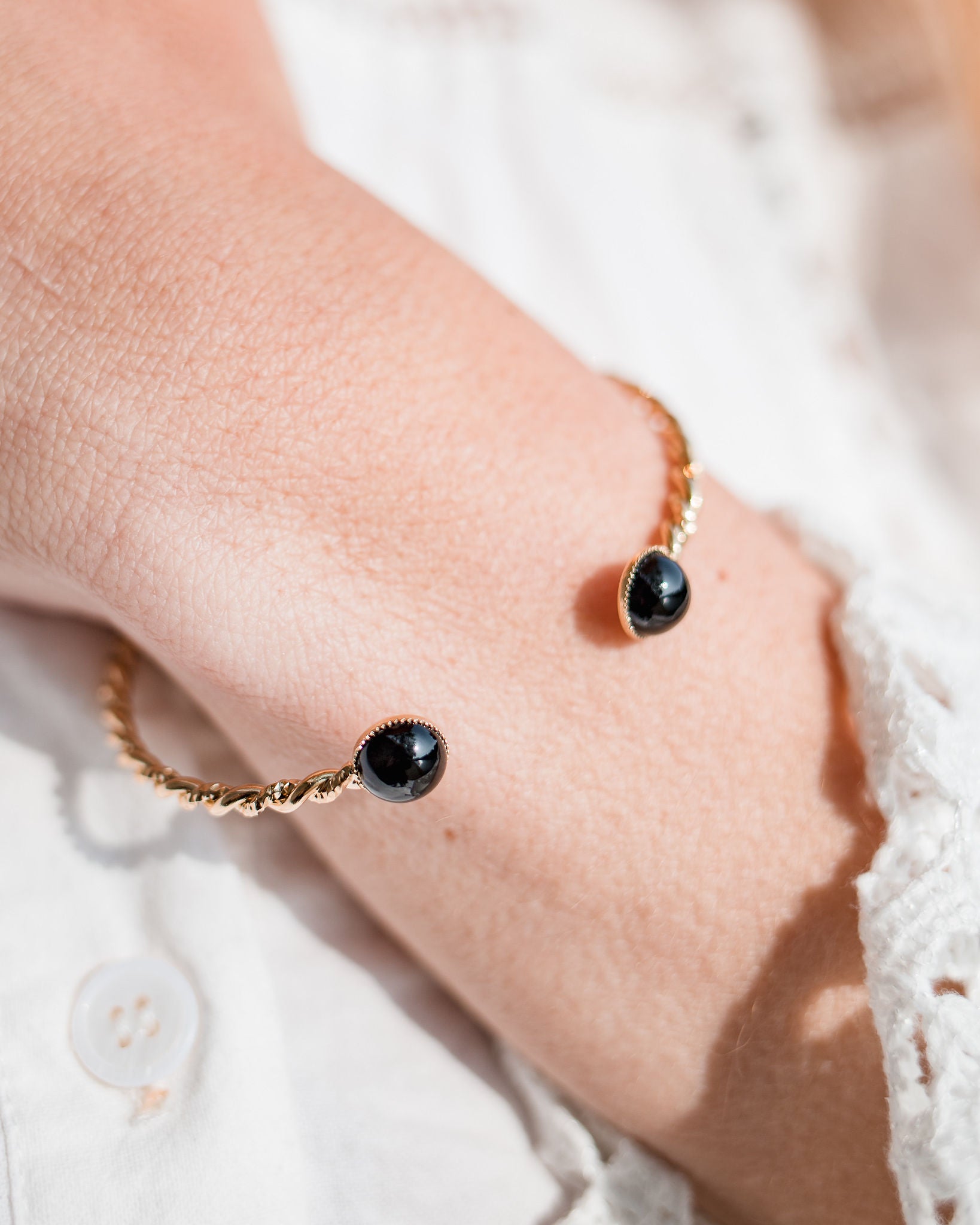 Gros plan sur le cabochon onyx du bracelet jonc Paul plaqué or